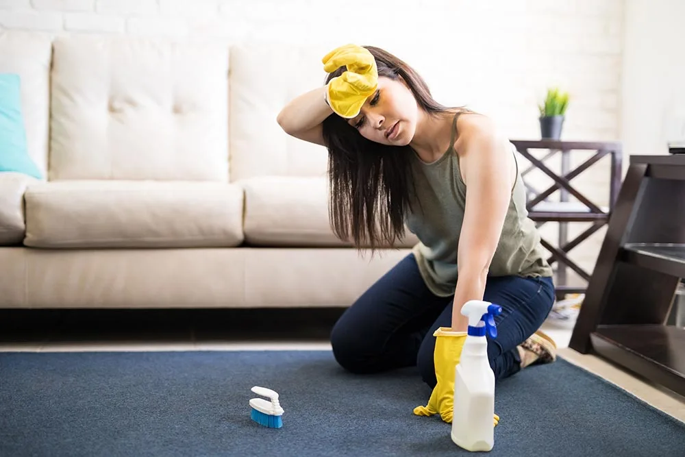 Tired housewife cleaning carpet